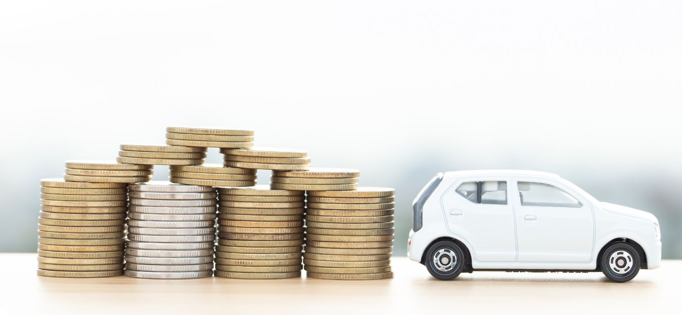 A small white toy car beside a stack of coins.