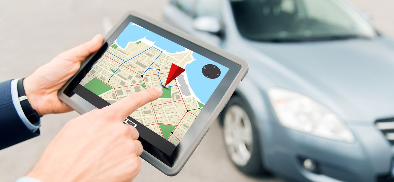 Someone holding a tablet in front of a car, with a GPS app open.