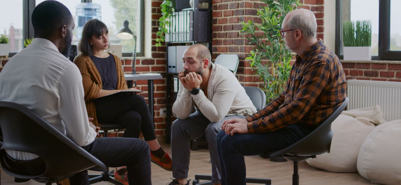 A group of people talking in a group, in a rehab treatment center.