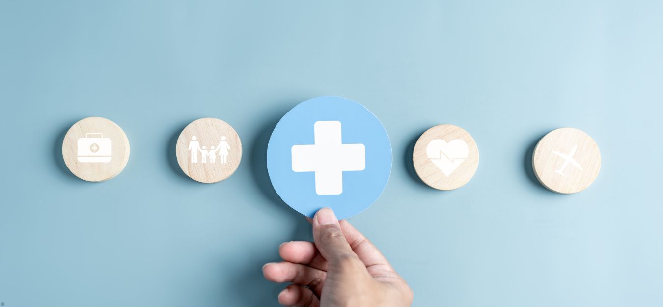 A hand holding a paper circle with a white cross on it, over a blue background.