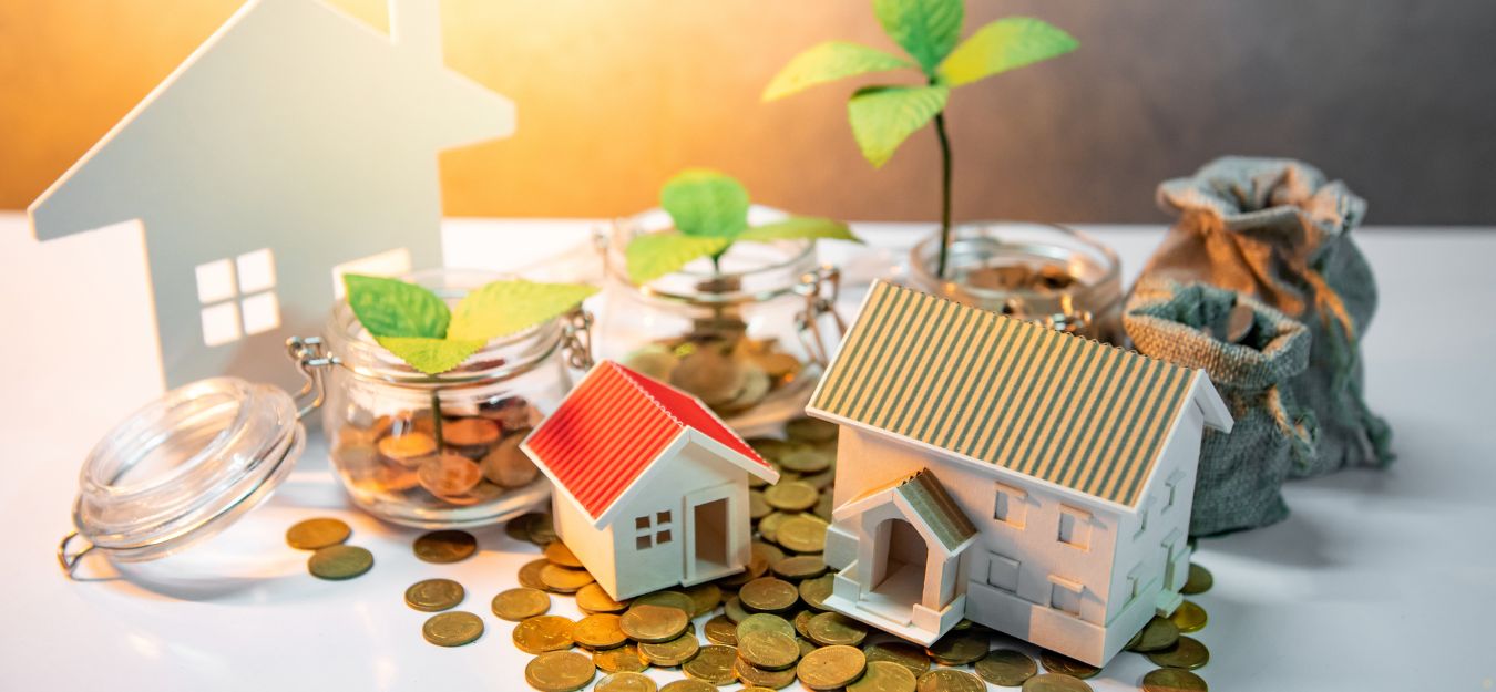 Small toy houses on a pile of coins.