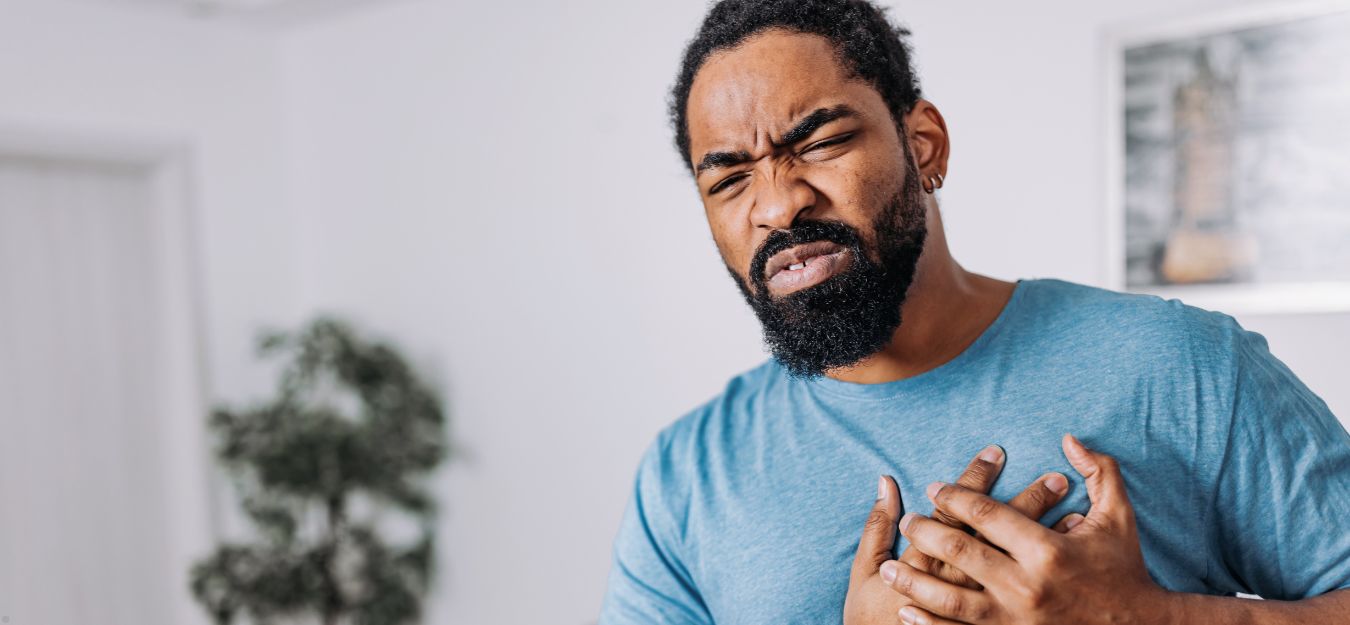 A man holding his chest, experiencing chronic chest pain.